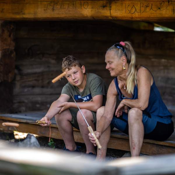 En dame og en gutt som griller pølser i gapahuken