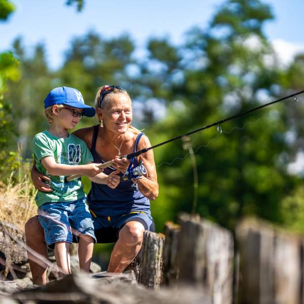 En eldre dame og en liten gutt som fisker
