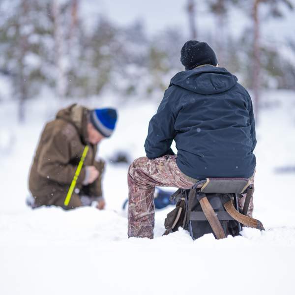 To personer som sitter på isen og isfisker