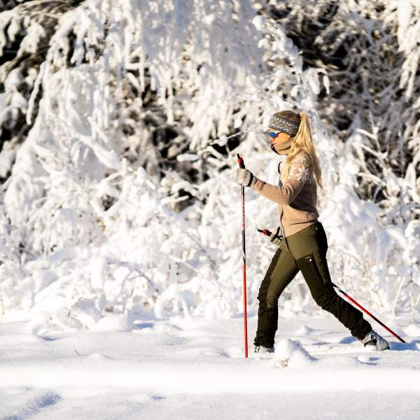 Dame på skitur i strålende solskinn i skogen