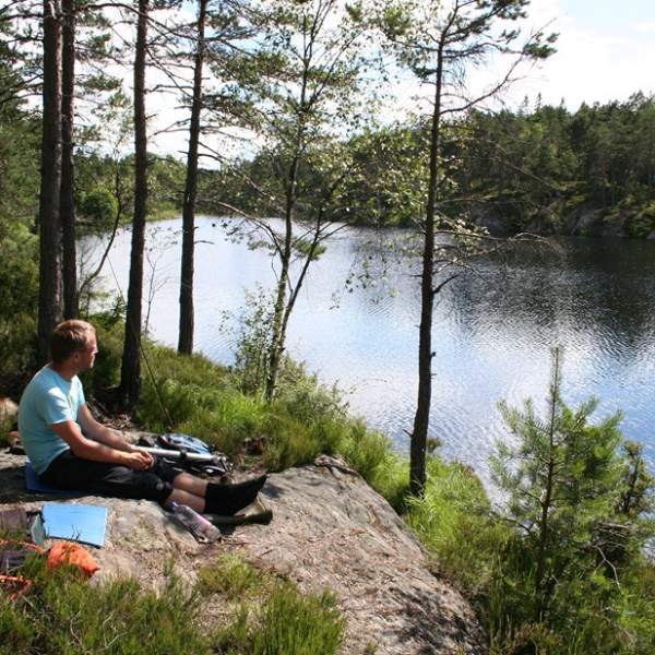En gutt som sitter ved ett vann og titter utover