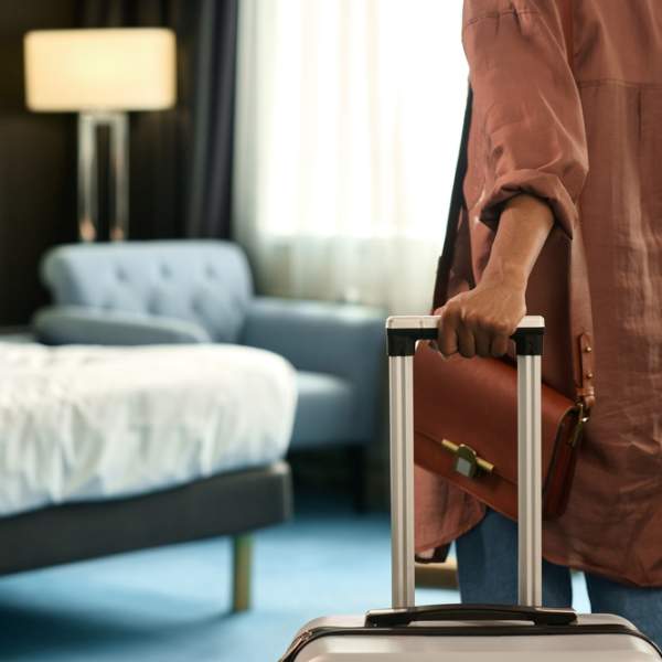 Kvinne triller kofferten sin inn på et hotellrom