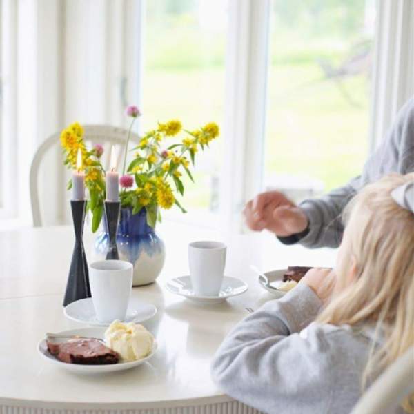 To som sitter ved ett bord med mat og blomster