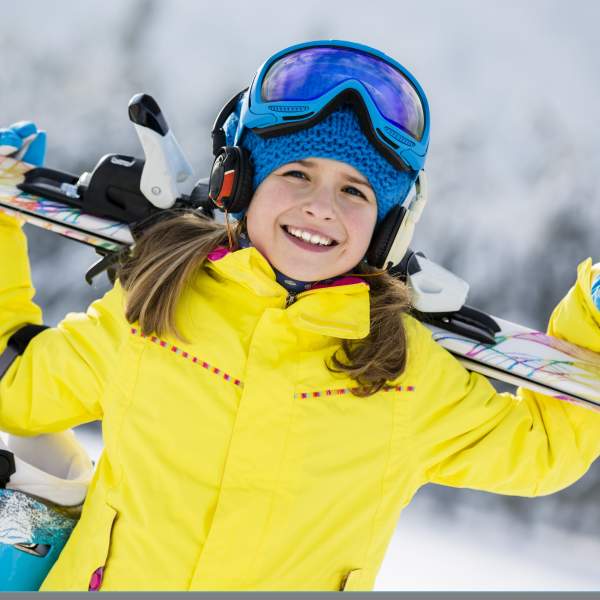 Jente i gul skijakke som holder alpintski