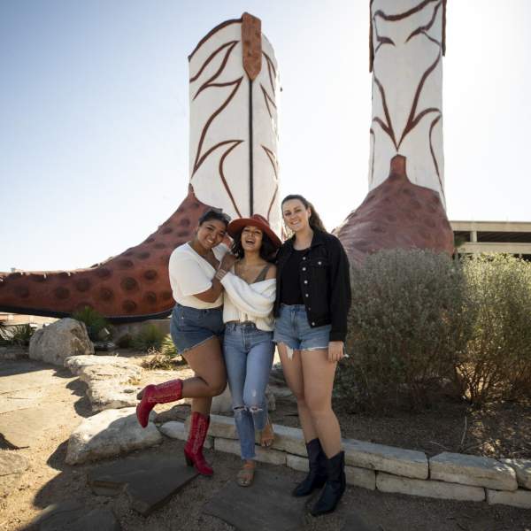 Three girls in front of cowboy boots sculpture