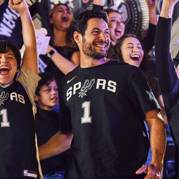 Fans cheering at game wearing Spurs shirts and jerseys
