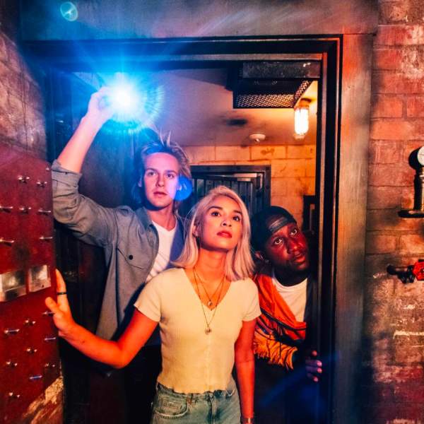 Girl and two boys opening door and holding flashlight.