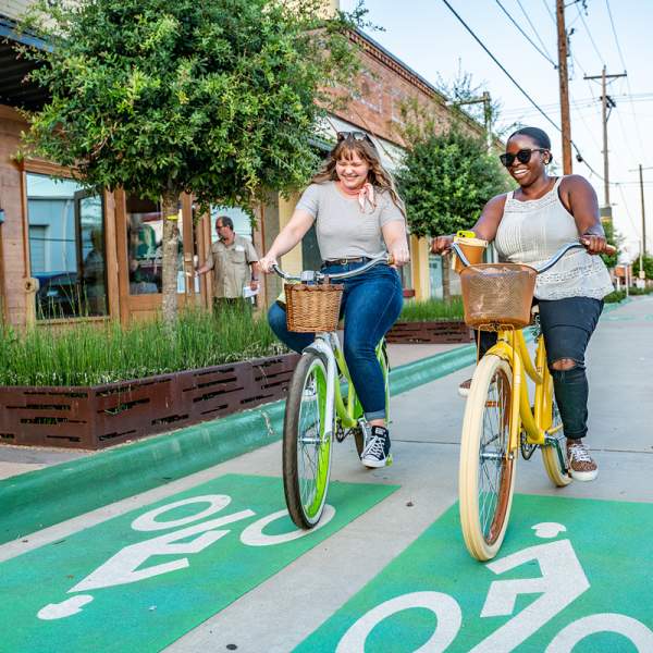 Two women riding bikes in Bossier City's East Bank District & Plaza
