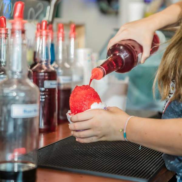 Photo of bright red syrup being poured over shaved ice