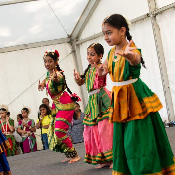 Group of young women, dressed in colourful attire, performing traditional dance at the Southampton Mela Festival