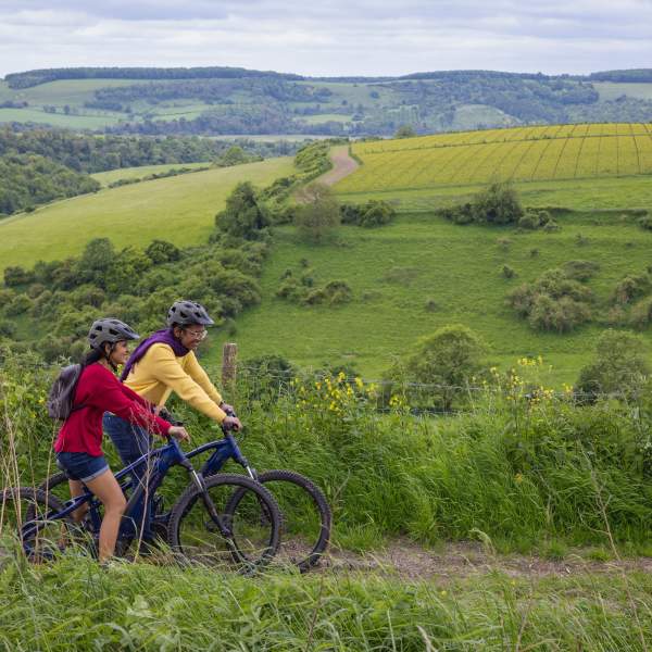 A man and woman riding mountain bikes along a track, on the South Downs