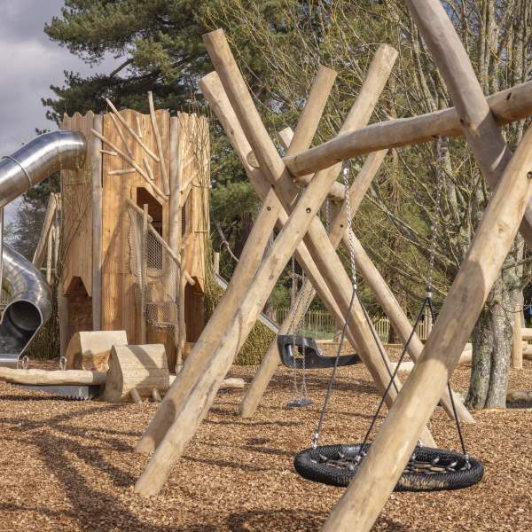 outdoor play area at Leonardslee Lake & Garden showing wooden climbing structures and a spiral slide