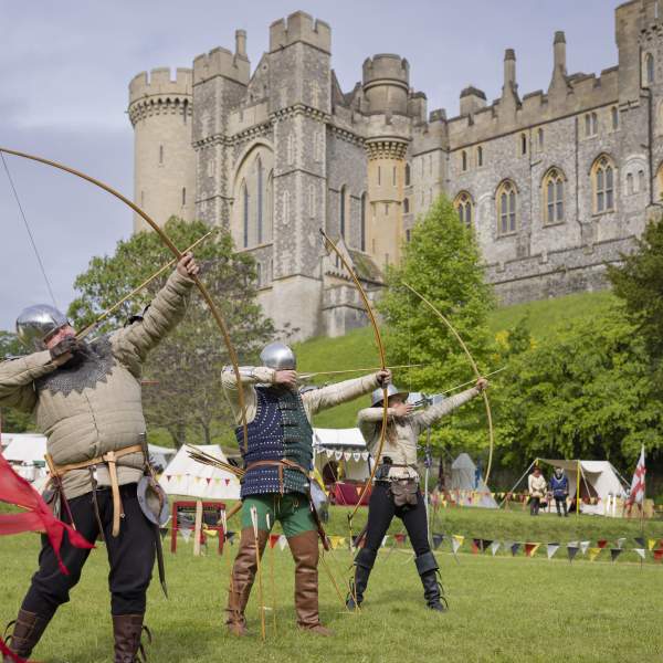Three archers taking aim in medieval costume in the grounds of Arundel Castle in Sussex
