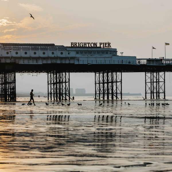 Brighton pier at low tide with the sun rising in the background
