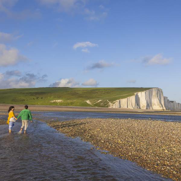 A couple walk in the water at low tide near Seven Sisters