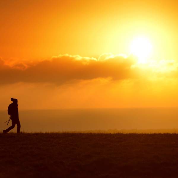 A lone walker on the South Downs in Sussex at sunset