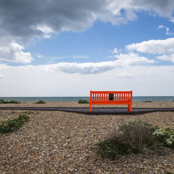 A shingle beach with red bench