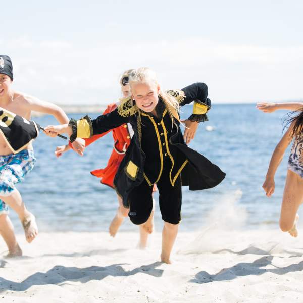 Happy children dressed as pirates on a beach in Kristiansand