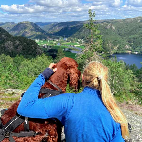 Girl and her dog on top of the mountain with view to the valley. Photo