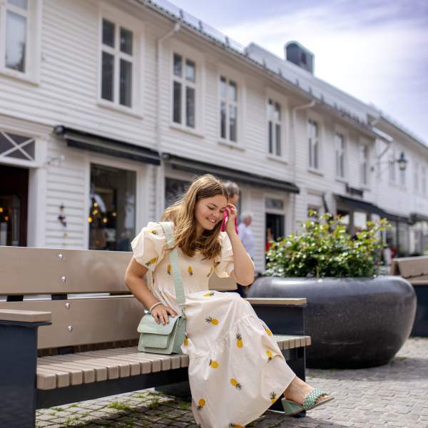 Jente som sitter på en benk i gågata i Mandal