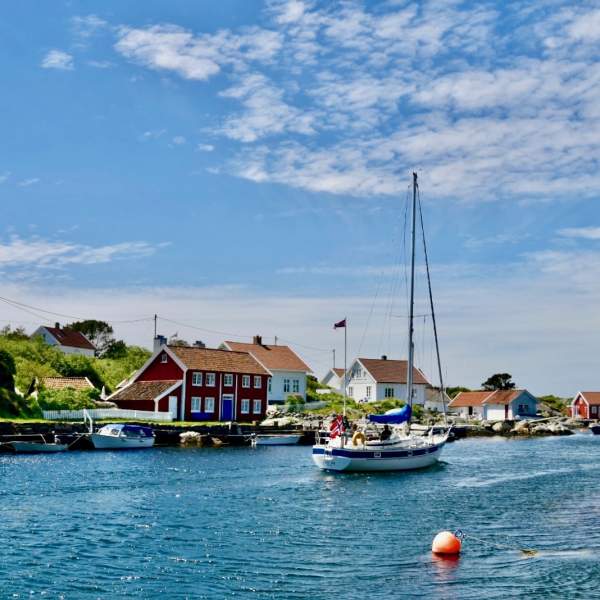 Seilbåt i sund, sørlandshus og blå himmel
