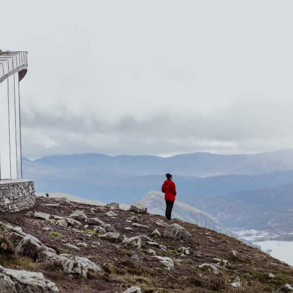 Kvinne i rød jakke ser på fjellandsskapet på Hovden.