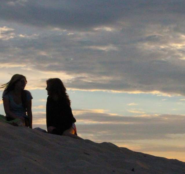 Two girls sitting on a hill talking