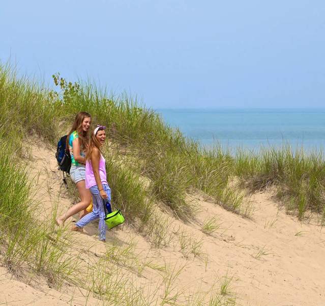 2 women walking dune the dunes towards the water