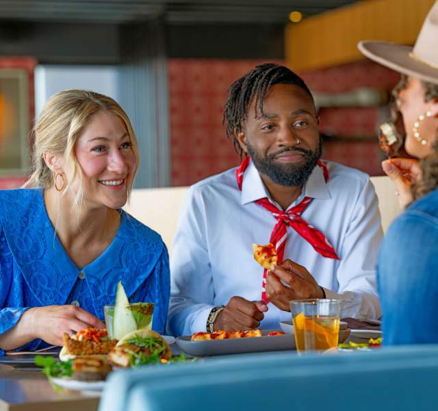 People enjoying food and conversation at a table at the Linger restaurant in Denver, Colorado.