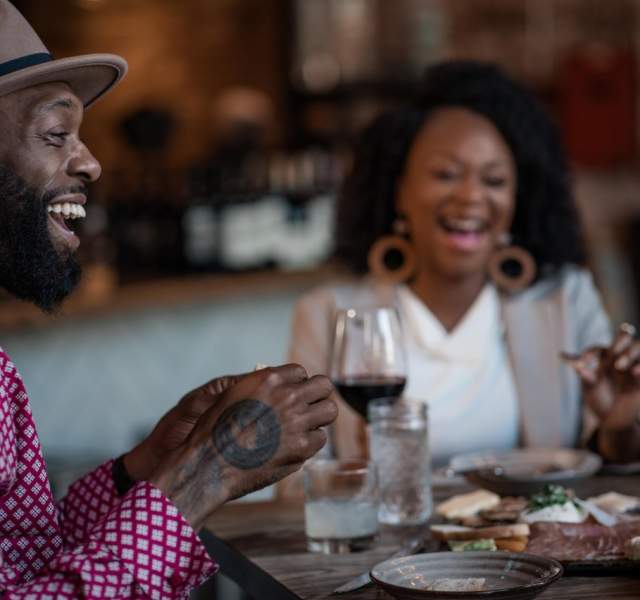 Two people laugh as they eat at a Denver restaurant with small plates in front of them