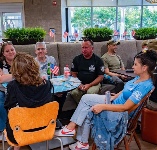 Group of adults seated together at tables, talking and reconnecting during a casual reunion gathering in Greater Fayetteville.