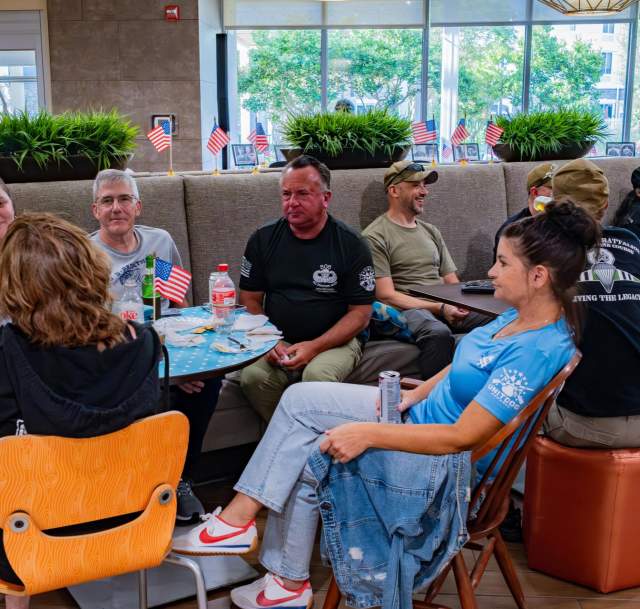 Group of adults seated together at tables, talking and reconnecting during a casual reunion gathering in Greater Fayetteville.