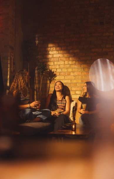 3 women at a bar sitting in a comfortable seating area laughing and talking