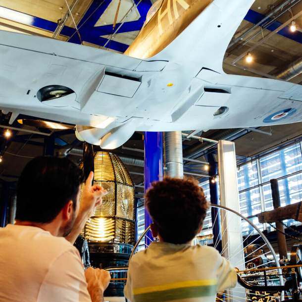A father and son look up at the underside of a WWII plane in the ThinkTank in Birmingham