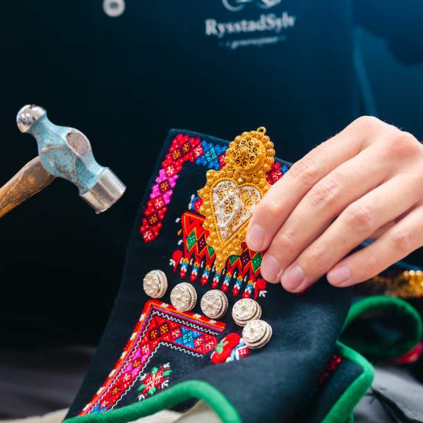 Hender som holder sølv på Setesdalsbunad