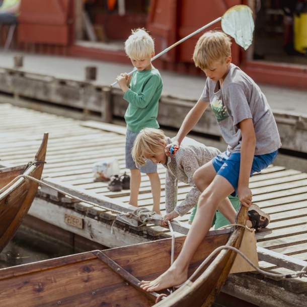 Barn fisker etter krabber fra robåter