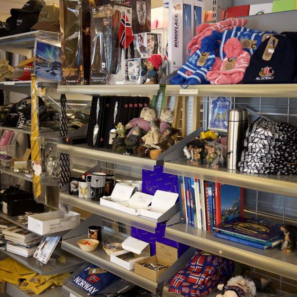 Hylle med klær, trollfigurer, termoser og andre suvenirer med norske motiver i Lyngdal Bokhandel.