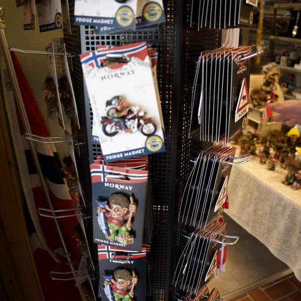 Roterende stativ med kjøleskapsmagneter formet som troll og elgskilt, merket med «Norway», i Lyngdal Bokhandel.