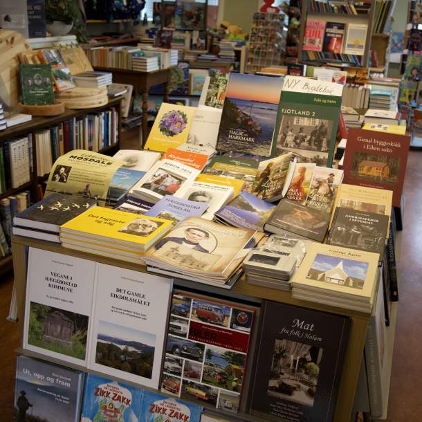 Bord med bygdebøker, romaner og lokalhistorie fra Lyngdal og nabokommuner utstilt i Lyngdal Bokhandel.