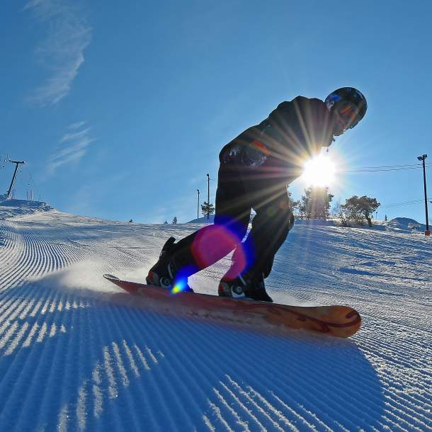 snowboarder i nypløyd bakke med sol og blå himmel i Setesdal