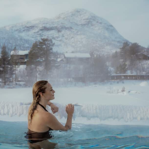 Kvinne ser utover vinterlandskap fra en varm akvedukt