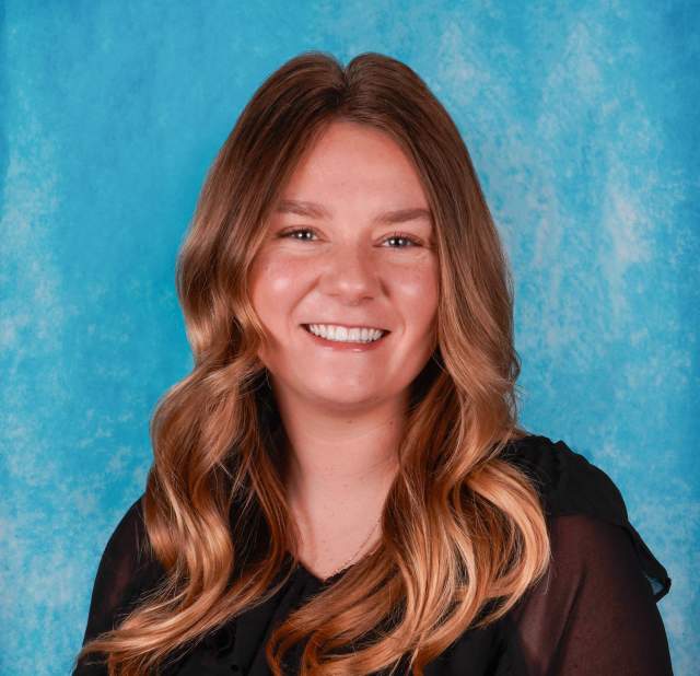 Woman's professional headshot on a blue background.