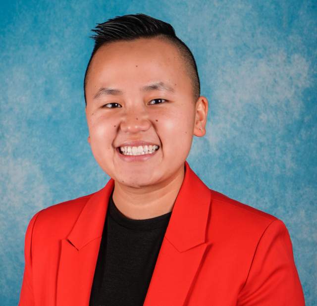 Professional headshot of a woman in a black shirt and red blazer.