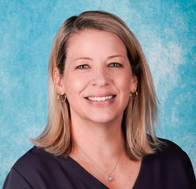 Woman's professional headshot on a blue background.