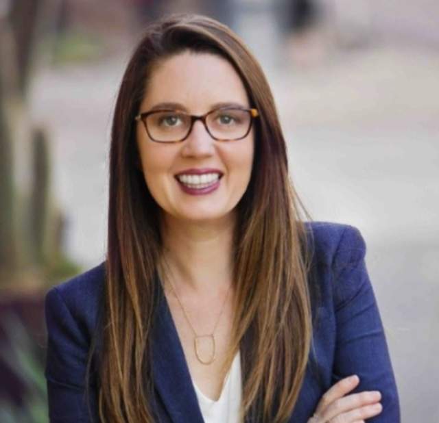 Headshot of woman standing with her arms crossed in a blazer.