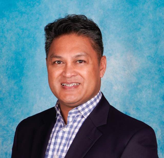 Man's professional headshot, wearing a blue plaid shirt and black blazer.