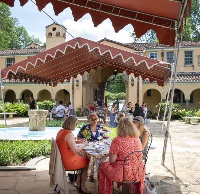 Groups of people dine outside Caramoor's buildings.