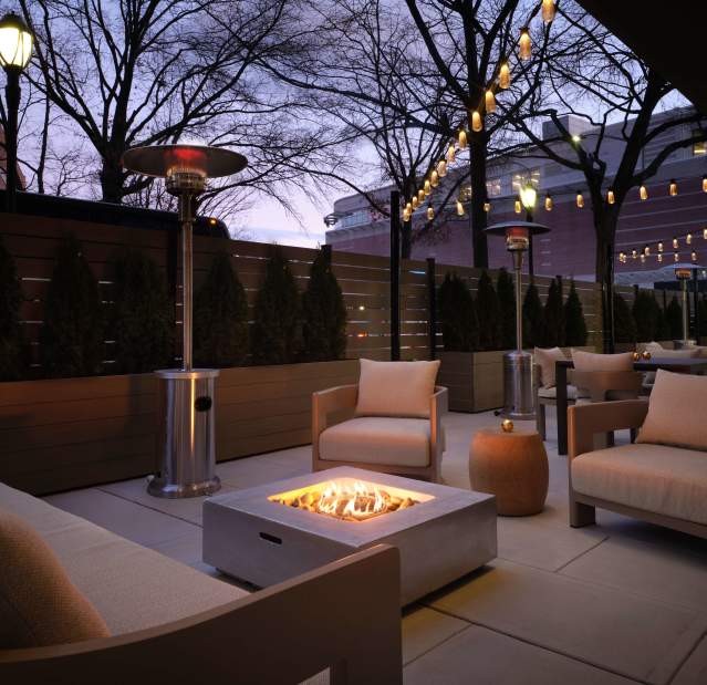 An outdoor patio at the Sonesta White Plains with a firepit and cushioned chairs.