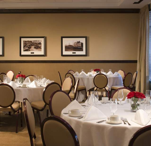 A banquet room in hues of yellow with tables set with white tablecloths and napkins.
