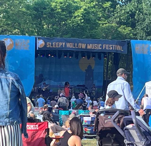A crowd is gathered on a sunny day in front of the stage at the Sleepy Hollow Music Festival.